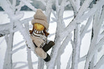 a stuffed animal sitting on top of a snow covered tree