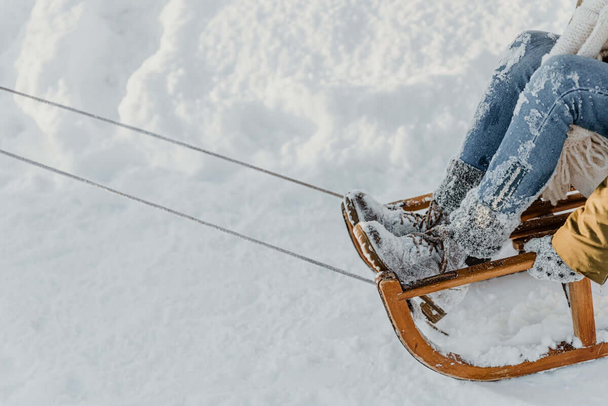a woman riding a sled down a snow covered slope