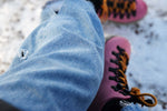 Pink boots with orange laces on snowy ground