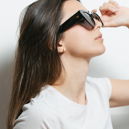 Mujer usando gafas de sol Hanukeii® Isla Tortuga Black, protegiendo sus ojos del sol.