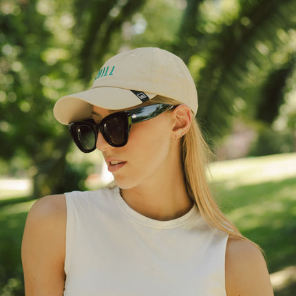 Mujer usando gafas de sol Hanukeii® Isla Tortuga Black / Black con gorra en un entorno natural.
