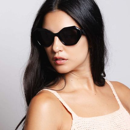Mujer usando gafas de sol Hanukeii® Moorea Black / Black con fondo neutro.