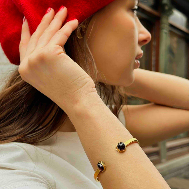 Mujer luciendo la Pulsera Sol Invictus, dorada con piedras negras, estilo elegante y moderno.