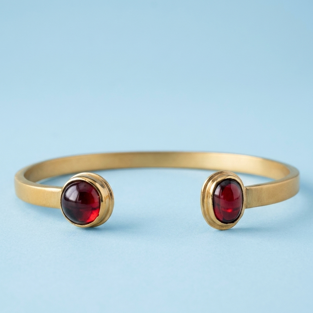 Pulsera Sol Invictus dorada con gemas rojas, accesorio elegante y moderno para cualquier ocasión